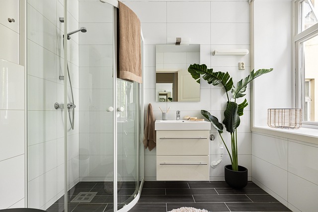 Clean bathroom remodel with glass shower, white vanity, black tile floor, and natural light